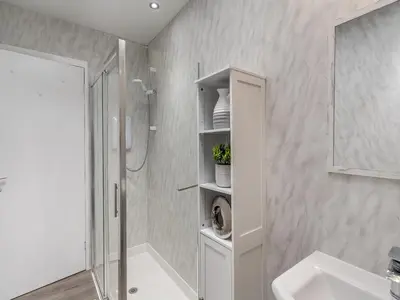 a white bathroom with a shower and a sink at The Mulberry in Lamlash