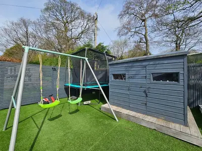 a playground with two swings in a yard at Kaimes Kip Stylish Edinburgh Five Bedroom Home in Edinburgh