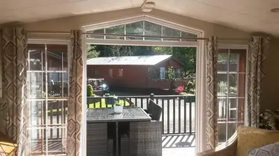 an open patio door with a table on a balcony at Jasper Lodge in Beautiful Glendevon Country Park Perthshire Scotland in Glendevon