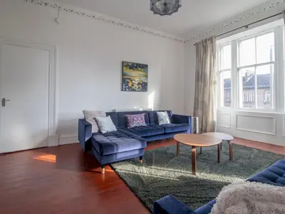 a living room with a blue couch and a table at Pass the Keys Victoria Road Queens Park View in Glasgow