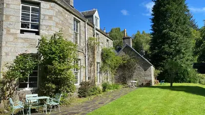 an old stone building with a table and chairs in a yard at Birch Tree Cottage in Killichonan