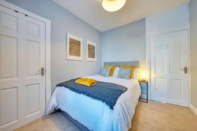 a bedroom with a bed with a blue blanket on it at 3-Bed Flat Free Parking 10 Mins to City Centre in Glasgow