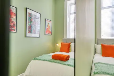 a bedroom with two beds with orange pillows and a mirror at 3-Bed Flat Free Parking 10 Mins to City Centre in Glasgow