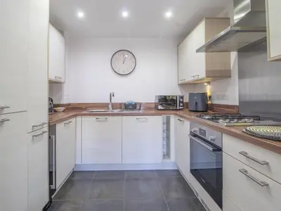 a kitchen with white cabinets and a clock on the wall at Pass the Keys Next to Braehead - Free Parking in Renfrew