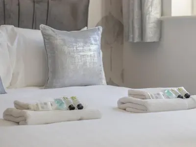 a white bed with two folded towels on it at Pass the Keys Next to Braehead - Free Parking in Renfrew