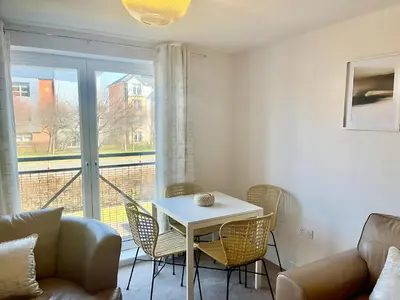 a living room with a table and chairs and a window at Pass the Keys Next to Braehead - Free Parking in Renfrew