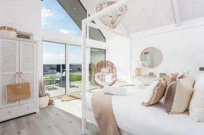 a white bedroom with a bed and a large window at No36 South Beach - Donnini Apartments in Troon