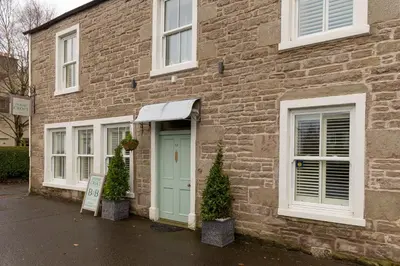 a brick building with a green door and two trees in front at Persie Croft Bed & Breakfast in Auchterarder