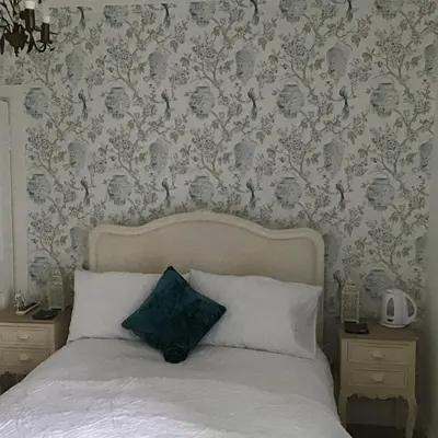 a bedroom with a bed and a wall with wallpaper at Persie Croft Bed & Breakfast in Auchterarder