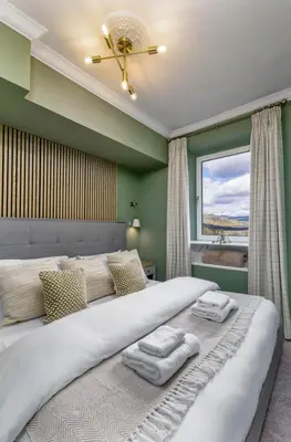 a bedroom with a large bed with two towels on it at Ochill View Apartment by Stirling Train Station in Stirling