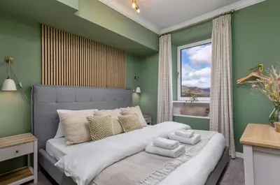 a bedroom with a bed with green walls and a window at Ochill View Apartment by Stirling Train Station in Stirling