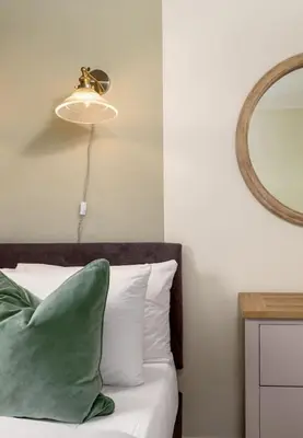 a bed with a green pillow and a mirror at Central Cathedral Apartment in Dunblane