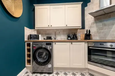 a kitchen with a washing machine and a sink at Stylish Penthouse Retreat in Stirling
