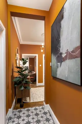 a hallway with orange walls and a large painting on the wall at Stylish Penthouse Retreat in Stirling