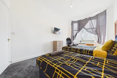 a bedroom with two beds and a window at West End Traditional Flat with Free Parking in Scotstoun West Station