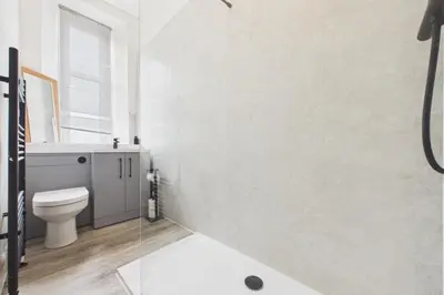 a white bathroom with a toilet and a shower at West End Traditional Flat with Free Parking in Scotstoun West Station