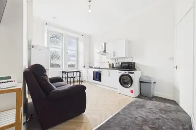 a living room with a couch and a washing machine at West End Traditional Flat with Free Parking in Scotstoun West Station