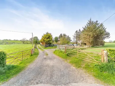 a dirt road in a field with a fence at Torr Cottage in Dalrymple