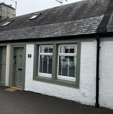a white house with a green door and window at Cosy Wee Cottage in Monkton