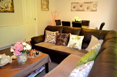 a living room with a brown couch and a table at Double room in riverside apartment - B in Glasgow