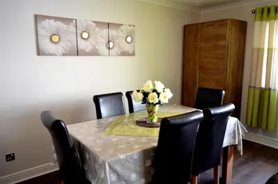a dining room table with a vase of flowers on it at Double room in riverside apartment - B in Glasgow