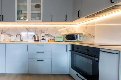 a kitchen with white cabinets and a microwave at John Neilson View - Coorie Doon in Paisley