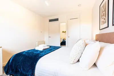 a white bedroom with a large bed with white pillows at John Neilson View - Coorie Doon in Paisley