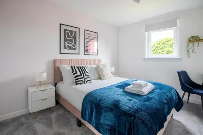 a bedroom with a bed with a blue blanket at John Neilson View - Coorie Doon in Paisley