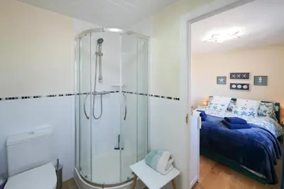 a bathroom with a shower and a bed at Caledonia by the Sea in Saltcoats