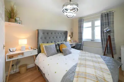 a bedroom with a bed and a lamp and a window at Caledonia by the Sea in Saltcoats