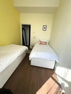 two beds in a room with yellow walls and wood floors at Coatbridge central apartment 20 min from Glasgow in Coatbridge