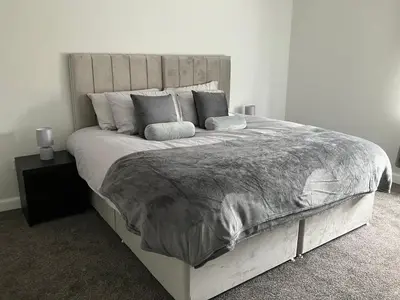 a bedroom with a large white bed with pillows at CONTRACTOR STAYS WELCOME newly refurbished 2 bedroom apartment sleeps 5 with free SECURE parking and WiFi Fully Fitted Kitchen with Washer Dryer Weekly bedding change and hoover Long Term Stay Rate available 3 miles from City Centre in Cowlairs