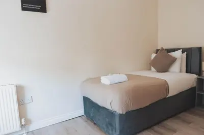 a small bedroom with a bed with white sheets at Stylish 3BR Home near Hampden No 264 with Free Parking in Glasgow