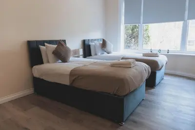 two beds sitting in a room with a window at Stylish 3BR Home near Hampden No 264 with Free Parking in Glasgow
