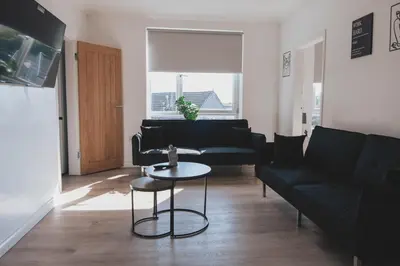 a living room with a black couch and a table at Stylish 3BR Stay by Hampden No 161 with Free Parking in Glasgow