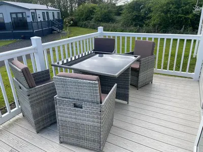 a patio with two chairs and a table on a deck at One Muirfield, Caravan at Turnberry in Turnberry