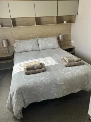 a bedroom with a large bed with two towels on it at One Muirfield, Caravan at Turnberry in Turnberry