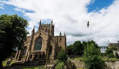 an old church with a bird flying in the sky at Stylish 1-Bed Apartment in the Heritage Quarter in Dunfermline