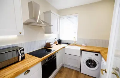 a kitchen with white cabinets and a washer and dryer at Stylish 1-Bed Apartment in the Heritage Quarter in Dunfermline