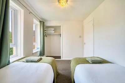 two beds in a room with two windows at 2BR Flat Parking Near City and Finnieston in Glasgow