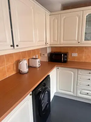 a kitchen with white cabinets and a washing machine at 3BR Flat Sleeps 6 West End Sights Driveway in Glasgow