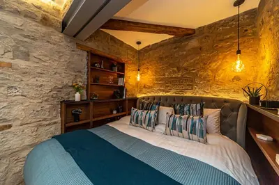 a bedroom with a large bed in a stone wall at Canon Cave in Edinburgh