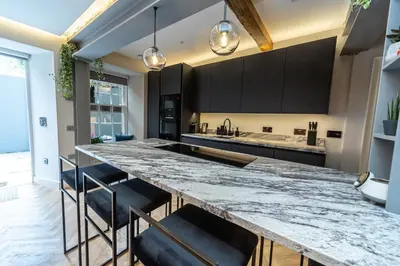 a kitchen with a large marble counter and black cabinets at Canon Cave in Edinburgh