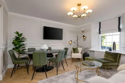 a living room with a dining room table and green chairs at Emerald Suite, The Stirling Residence in Stirling