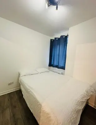 a bedroom with a bed and a window with blue curtains at Modern Apt commute to Edinburgh in Livingston