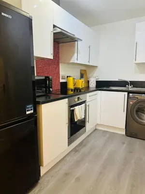 a kitchen with white cabinets and a black refrigerator at Modern Apt commute to Edinburgh in Livingston