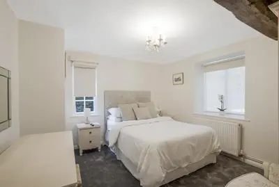 a white bedroom with a bed and a window at Beautiful 3 bedroom cottage close to Goodwood ! in Moffat