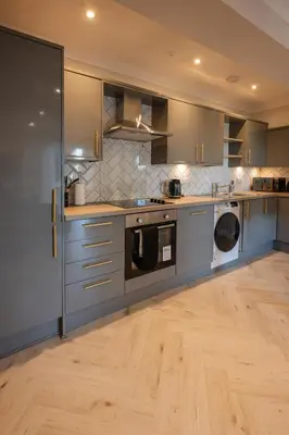 a kitchen with stainless steel appliances and wooden floors at Stirling Townhouse Apartment Btm in Stirling