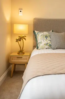 a bedroom with a bed and a table with a plant on it at Stirling Townhouse Apartment Btm in Stirling