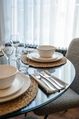 a glass table with plates and silverware on it at Stirling Townhouse Apartment Mid in Stirling